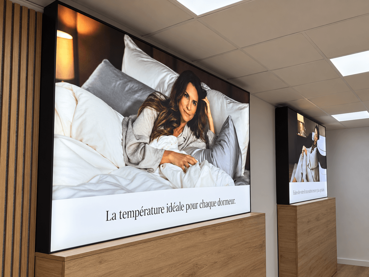 Cadres en toile tendue rétro-éclairés installés à l’intérieur du showroom Emma, mettant en valeur les visuels de marque.