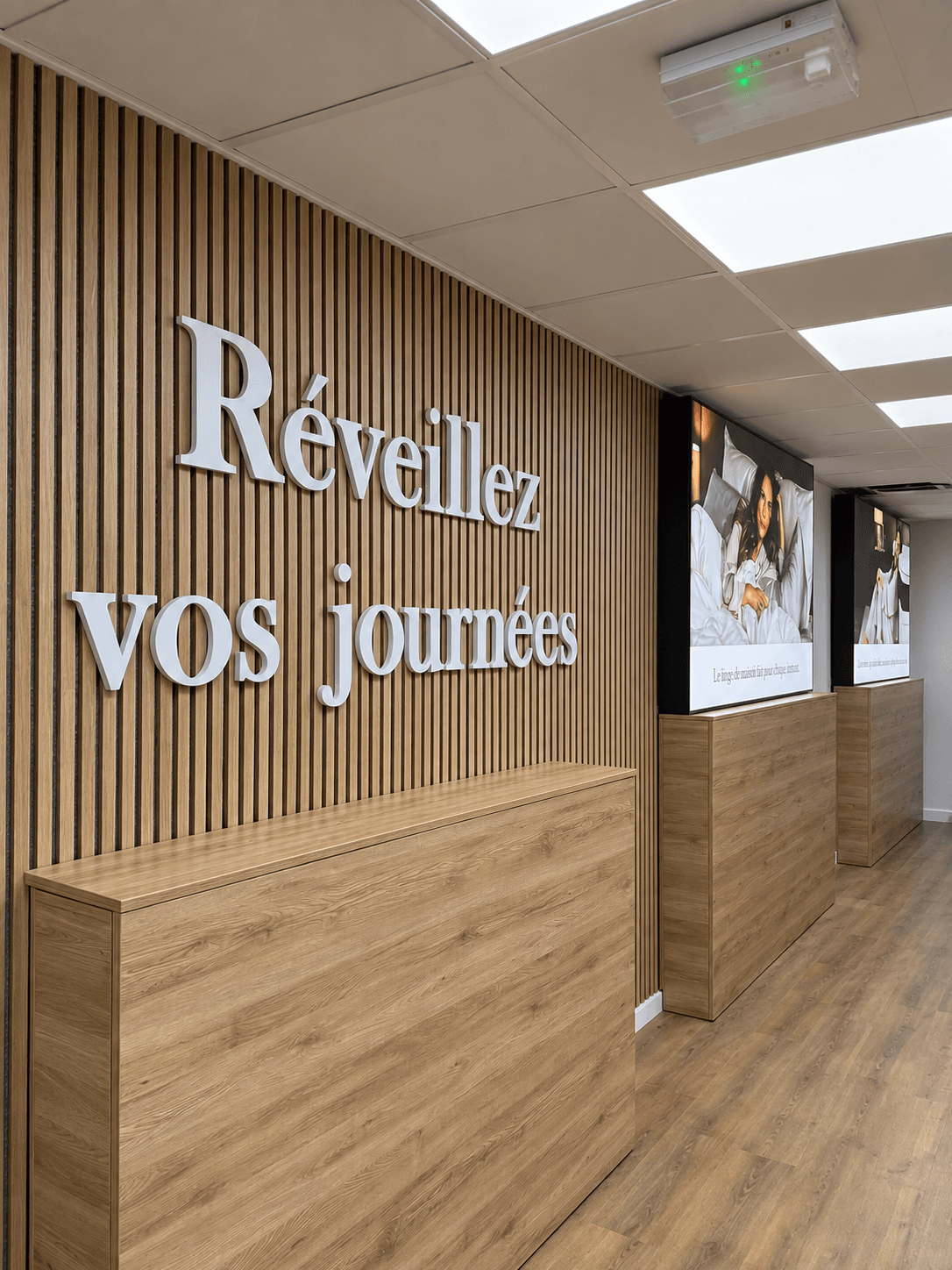 Lettrage Forex “Réveillez vos journées” fixé sur un mur en tasseaux, pour habiller l’intérieur du showroom Emma.