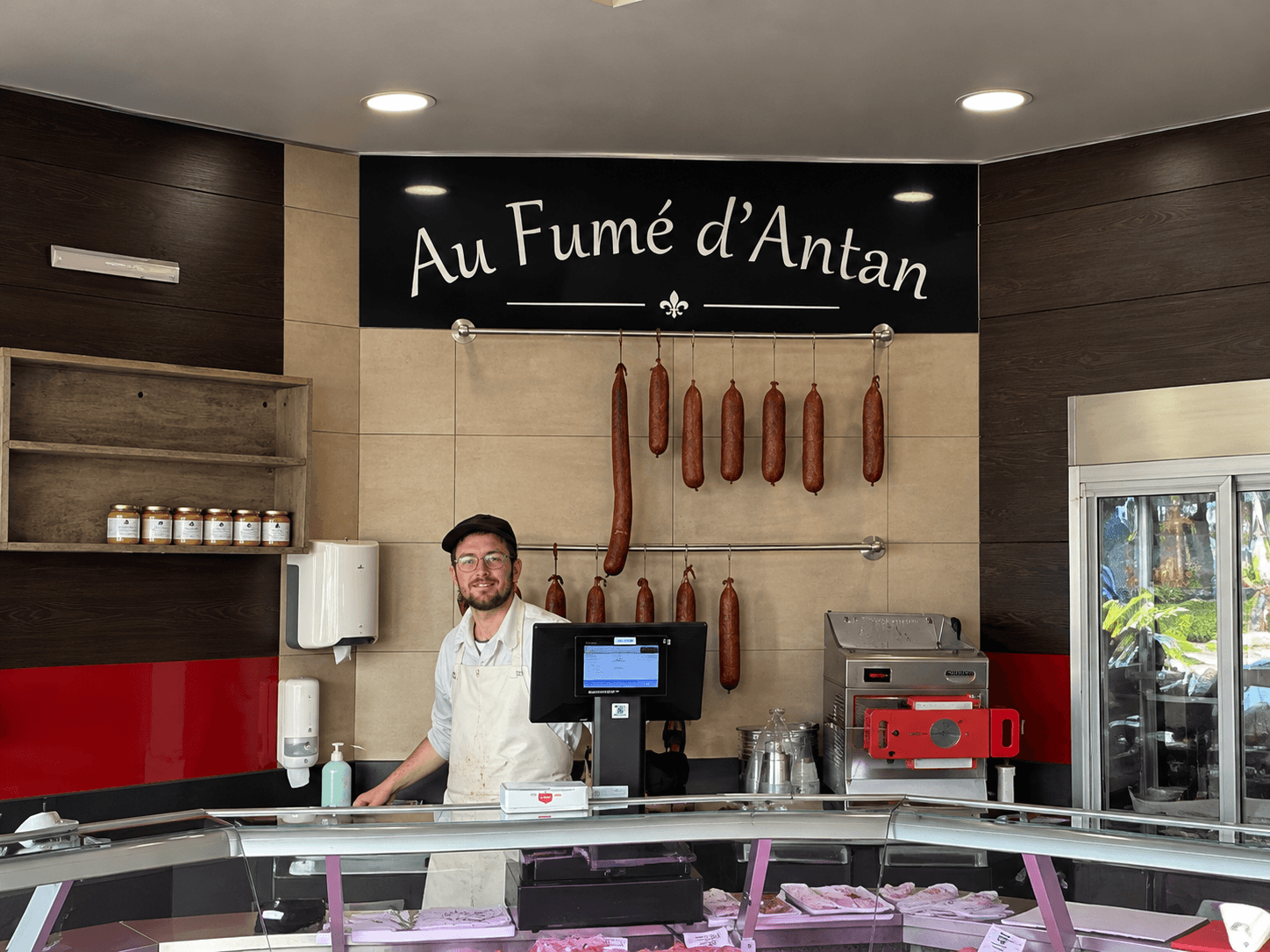 Intérieur de la boutique Au Fumé d’Antan avec enseigne en Forex posée au fond du magasin, au-dessus de l’espace de vente.