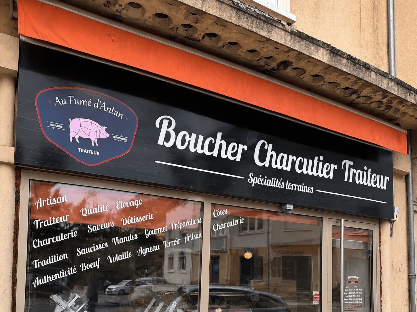 Façade de la boutique Au Fumé d’Antan avec caisson lumineux mettant en avant l’activité de boucherie, charcuterie et traiteur.